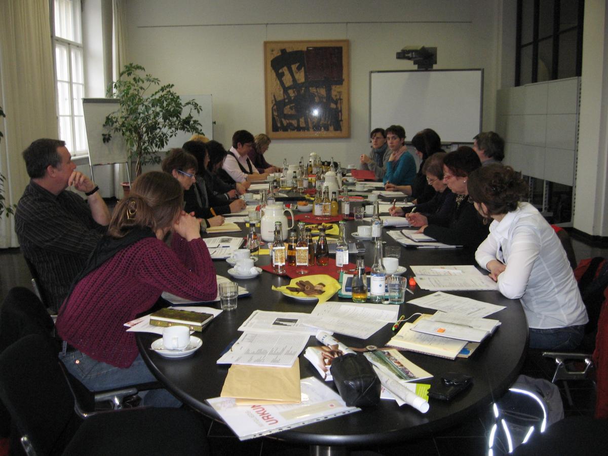 Mehrere Menschen in einer Sitzung an einem ovalen Tisch