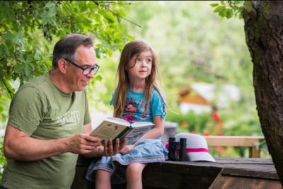 Ein Mann liest einem Kind aus einem Naturkundebuch vor